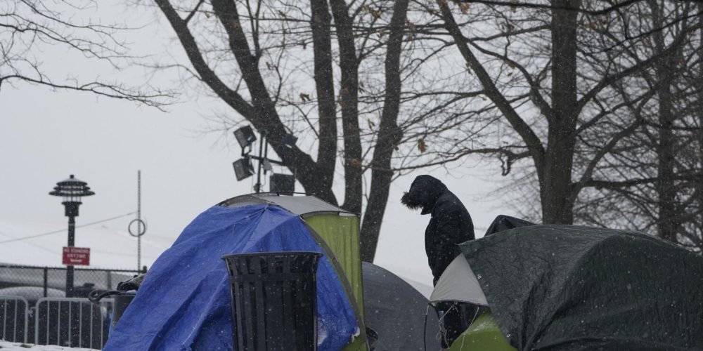 ARCHIVO - Un hombre permanece de pie junto a varias tiendas de campaña cercanas a un albergue para migrantes, el viernes 19 de enero de 2024, en la Isla Randall de Nueva York. (AP Foto/Seth Wenig)