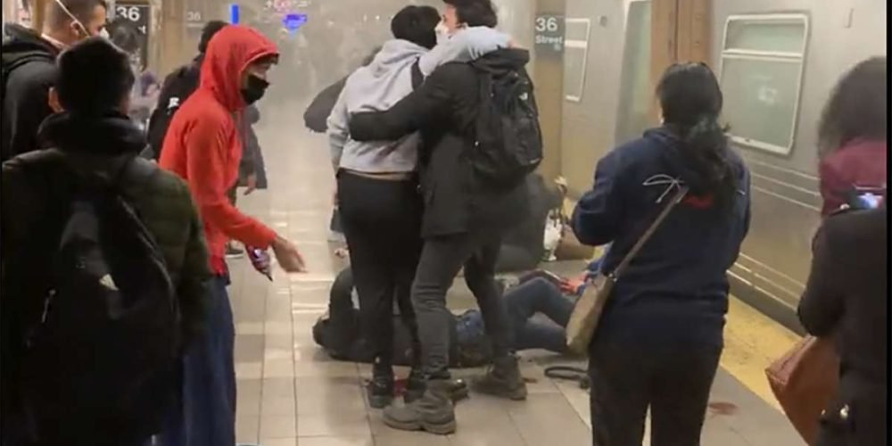 This photo provided by Will B Wylde, a person is aided outside a subway car in the Brooklyn borough of New York, Tuesday, April 12, 2022. A gunman filled a rush-hour subway train with smoke and shot multiple people Tuesday, leaving wounded commuters bleeding on a Brooklyn platform as others ran screaming, authorities said. Police were still searching for the suspect. (Will B Wylde via AP)